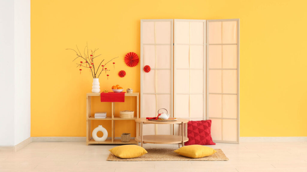 傳統中式客廳，米白色沙發搭配紅色抱枕，紅梅盆栽與掛畫增添雅致東方韻味。